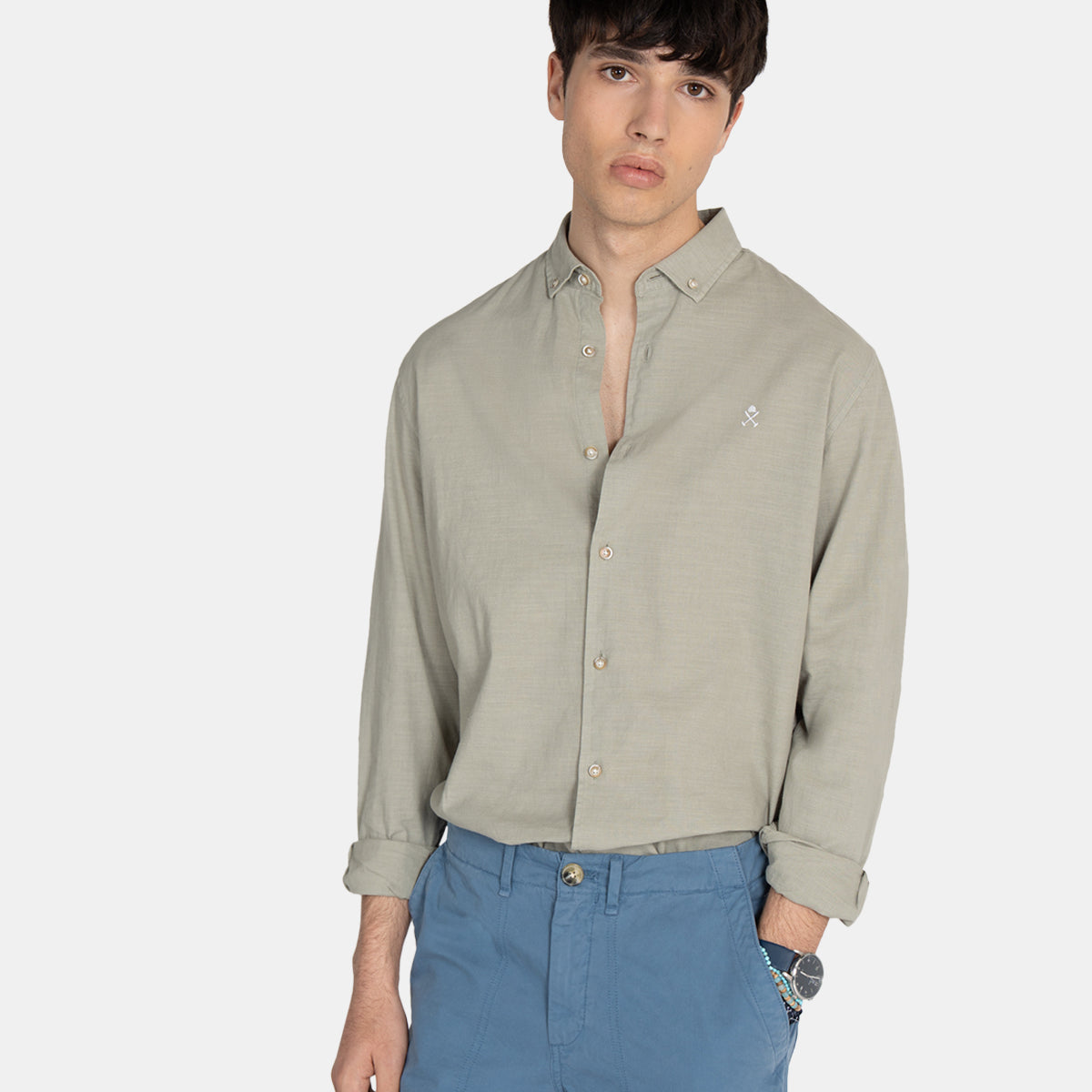 Modelo con camisa Royal Academy en verde gris remangada, combinada con bermudas azules en plano medio