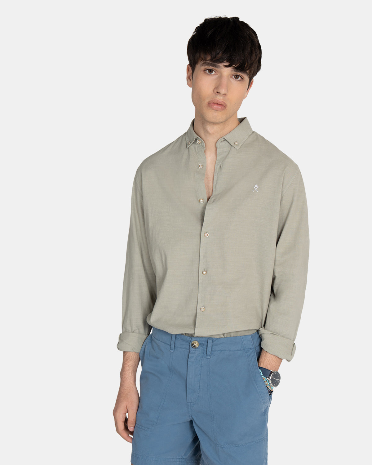 Modelo con camisa Royal Academy en verde gris remangada, combinada con bermudas azules en plano medio
