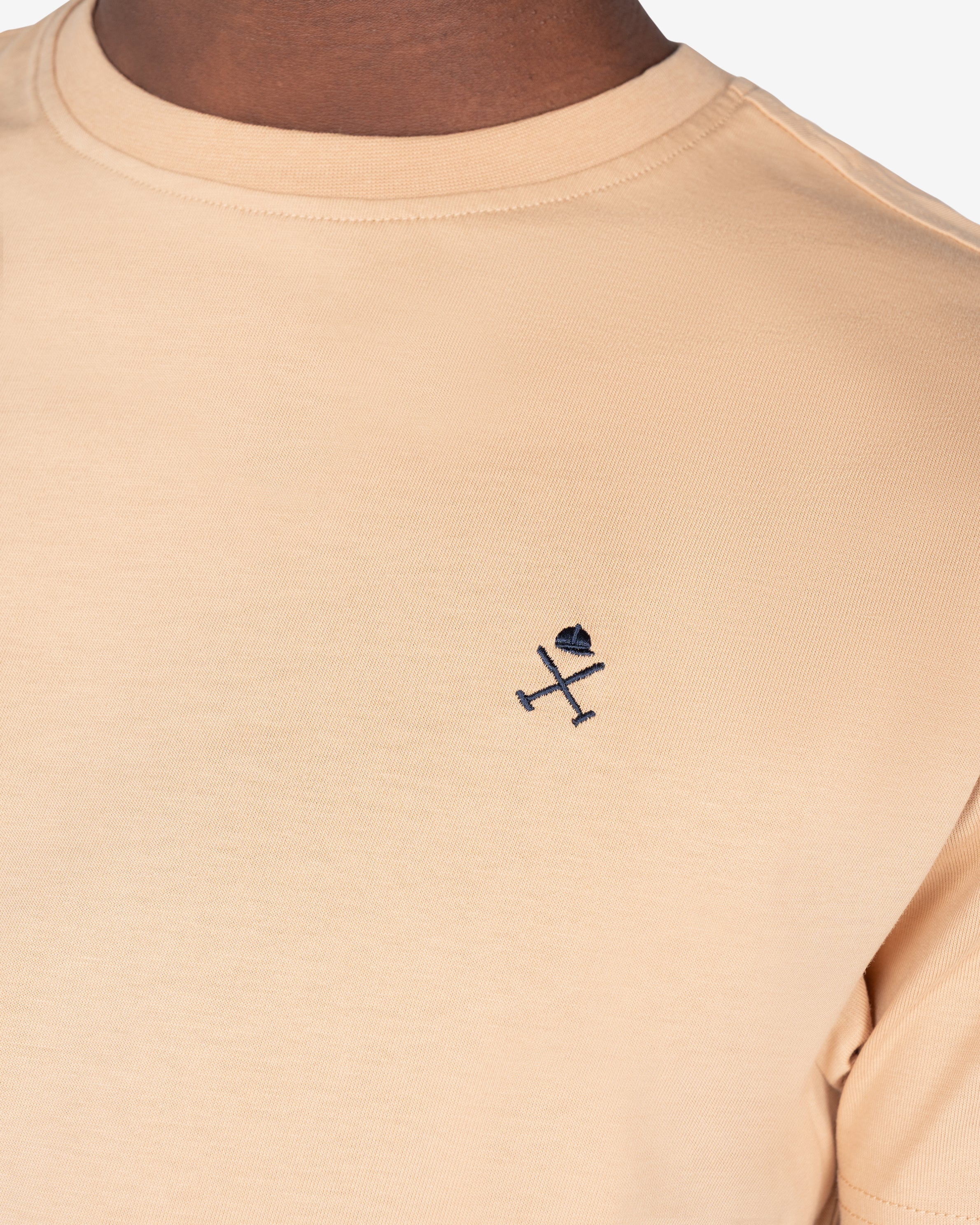 Detalle del logo bordado en azul marino sobre camel de la camiseta PARADISE de Harper & Neyer