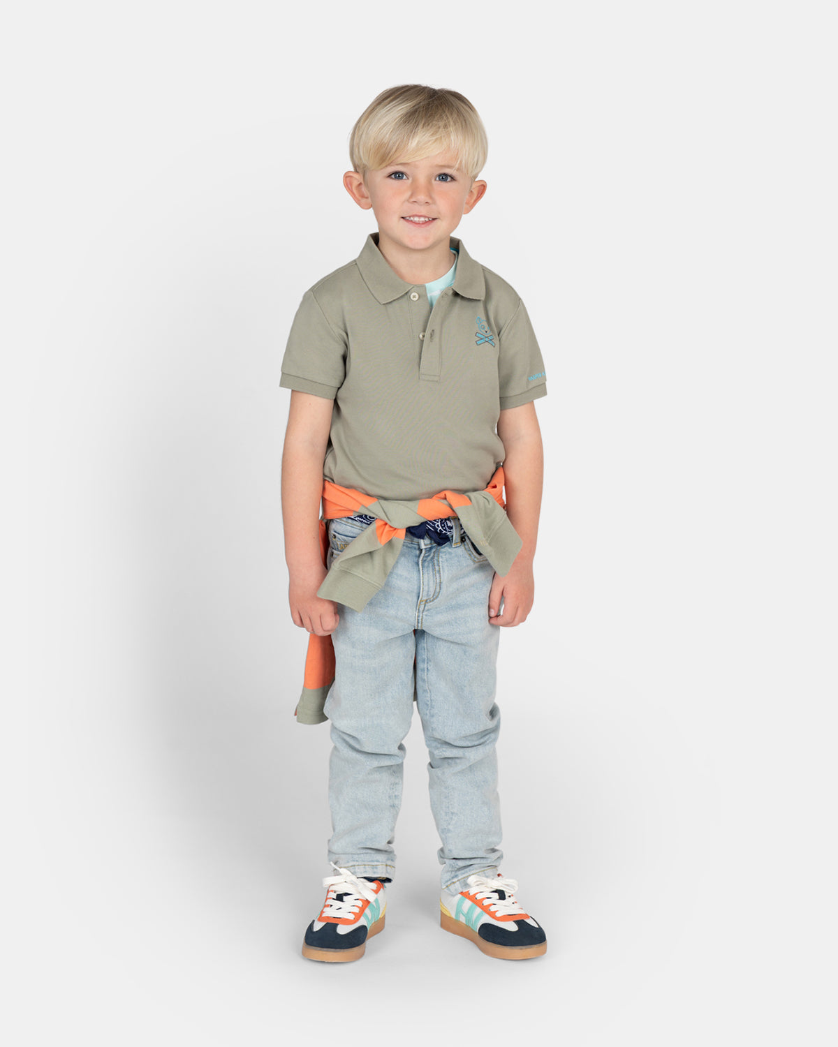 Polo Pirate Kids de Harper & Neyer en verde gris con niño, combinado con vaquero claro y sudadera naranja anudada