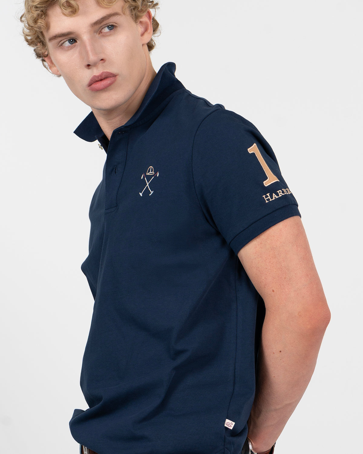 Detalle del cuello y tapeta del polo WINNER azul marino de Harper & Neyer con bordado de casco y mazos de polo