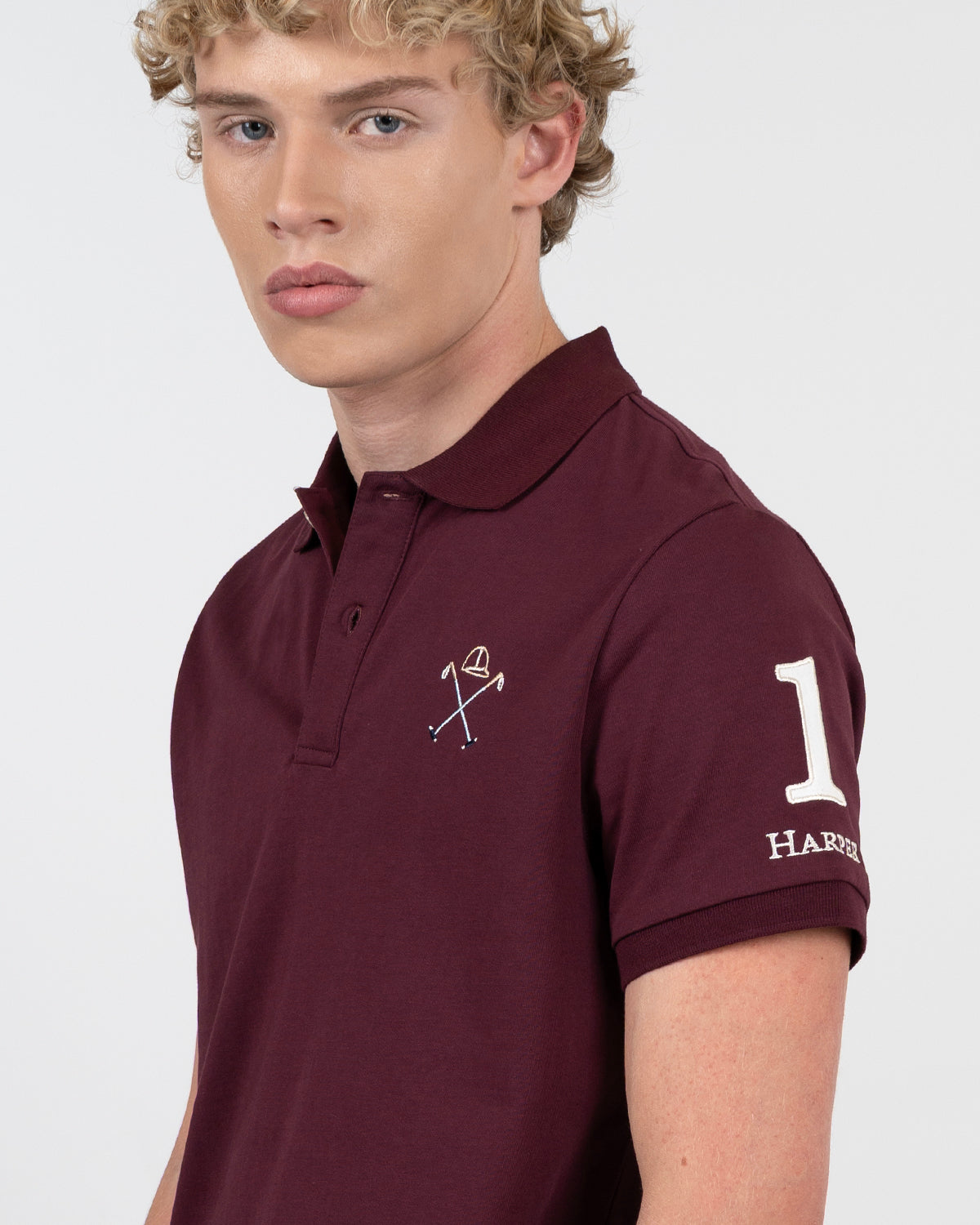 Detalle del cuello y tapeta del polo WINNER burdeos de Harper & Neyer con número uno blanco en la manga