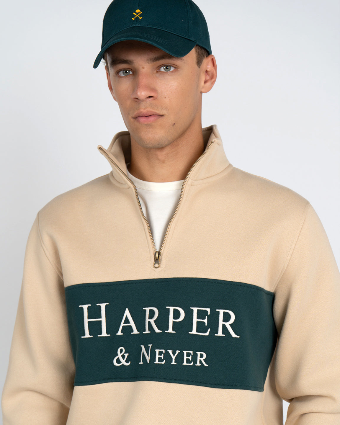 Sudadera Half-Zip Maryland de Harper & Neyer en camel con panel verde bosque, gorra y sneakers verdes