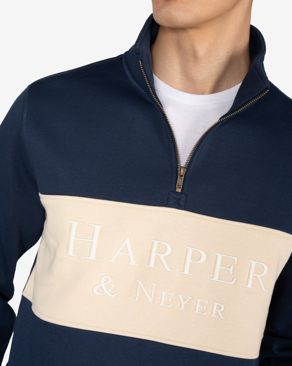 Detalle de la media cremallera dorada y logo Harper Neyer bordado en blanco crudo sobre panel de la sudadera MARYLAND azul marino
