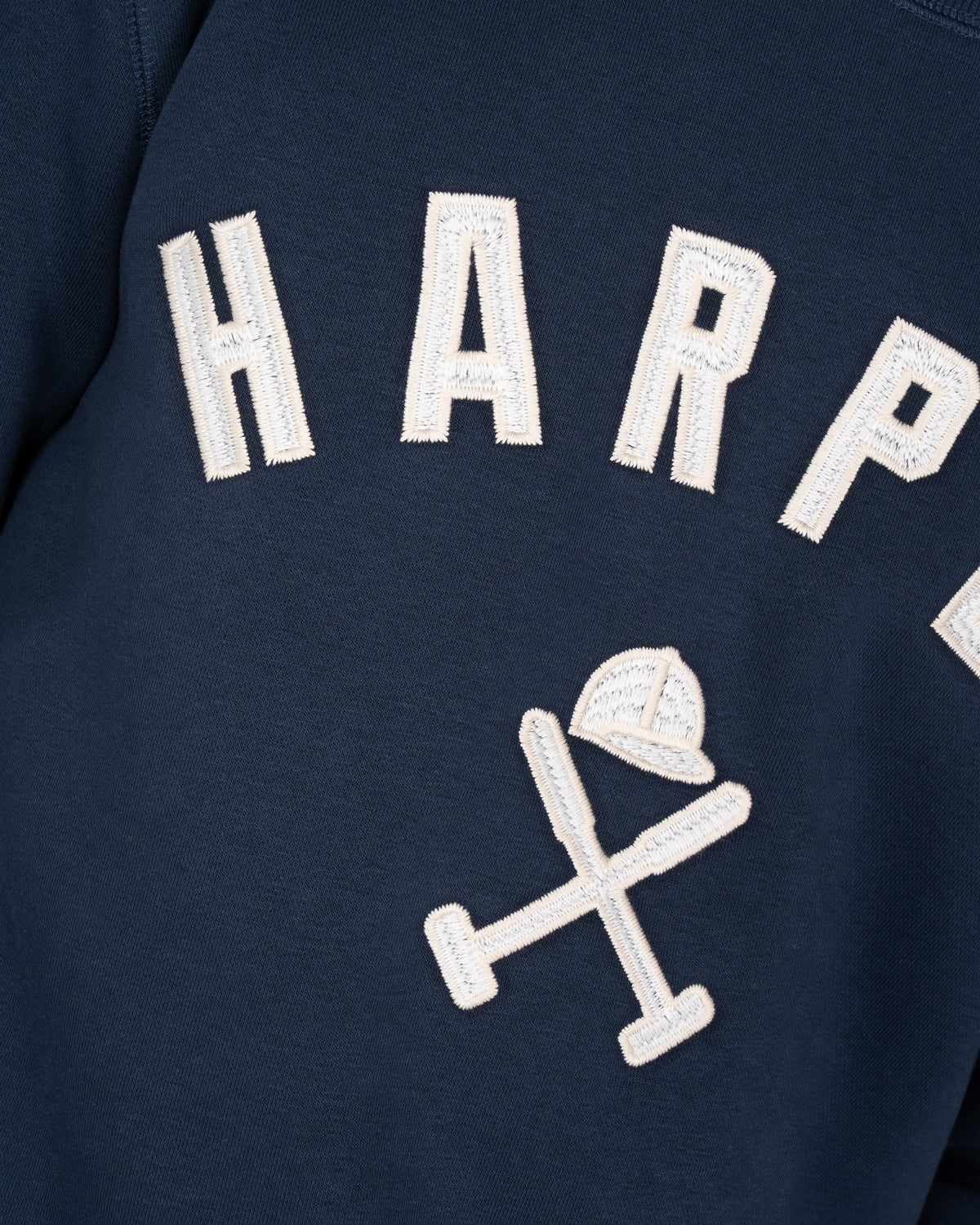 Detalle del bordado HARPER en appliqué crudo y casco de polo con mazos de la sudadera NEW ENGLAND azul marino