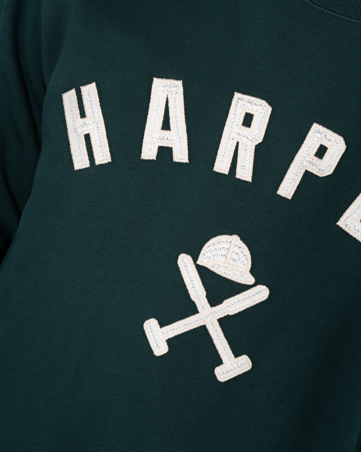 Detalle del bordado HARPER en appliqué crudo y casco de polo con mazos de la sudadera NEW ENGLAND verde botella