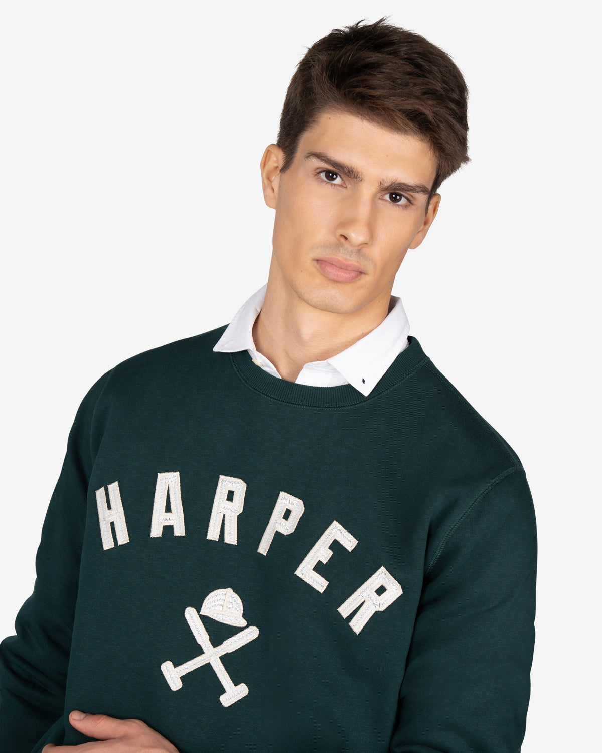 Sudadera NEW ENGLAND de Harper & Neyer en verde botella, plano medio con HARPER varsity y camisa blanca asomando