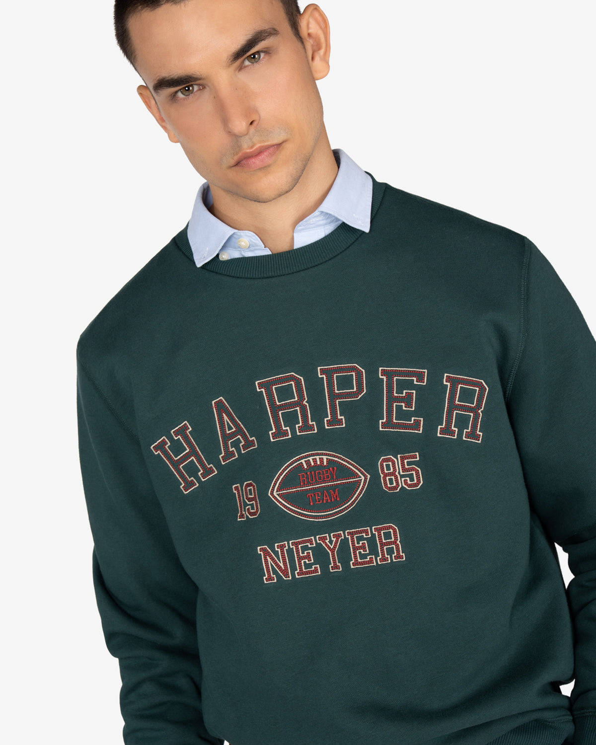 Sudadera RUGBY de Harper & Neyer en verde botella, plano medio con estampado college y oxford asomando por el cuello