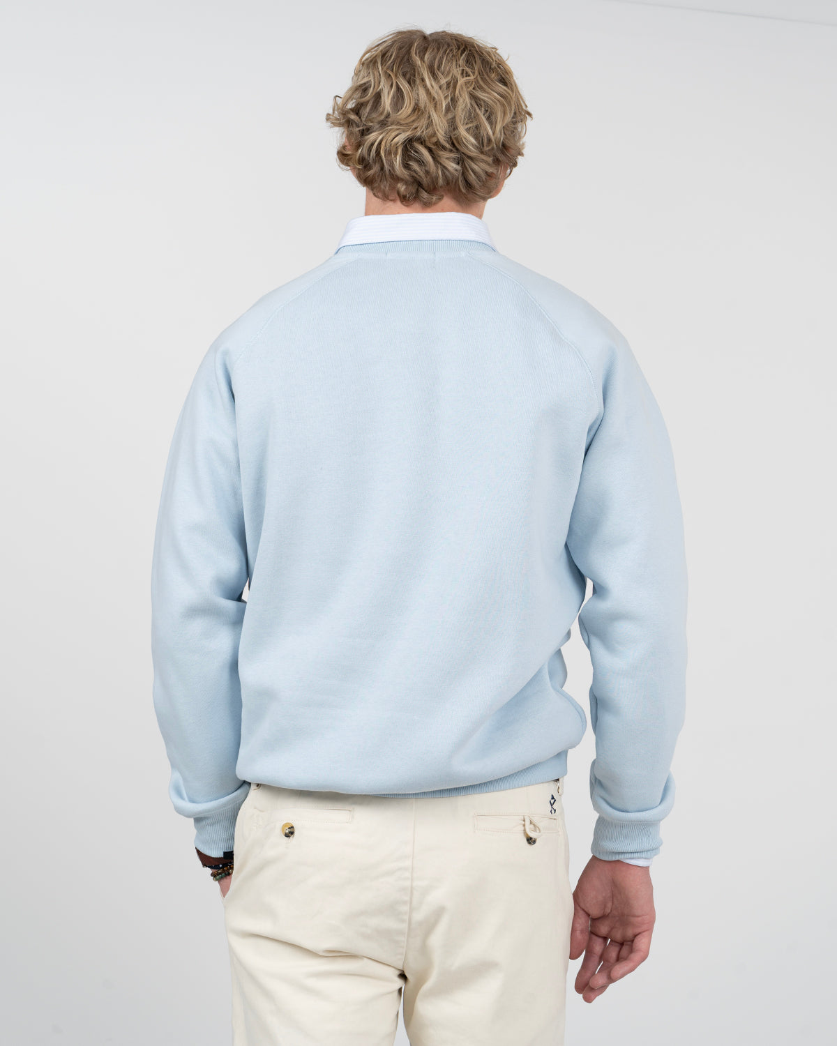 Sudadera VICTORY en algodón azul cielo de Harper & Neyer, vista trasera con manga ranglan sobre camisa de rayas
