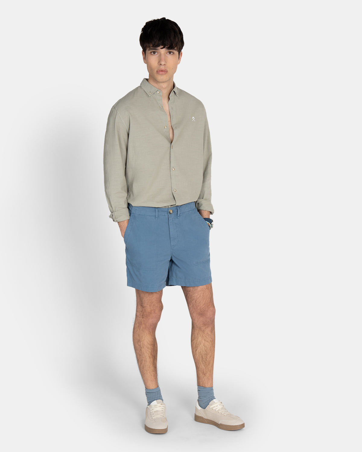 Camisa Royal Academy de Harper & Neyer en verde gris con modelo, combinada con bermudas azules y sneakers blancas