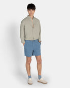 Camisa Royal Academy de Harper & Neyer en verde gris con modelo, combinada con bermudas azules y sneakers blancas