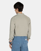 Vista trasera del modelo con camisa Royal Academy en verde gris remangada sobre bermudas azules