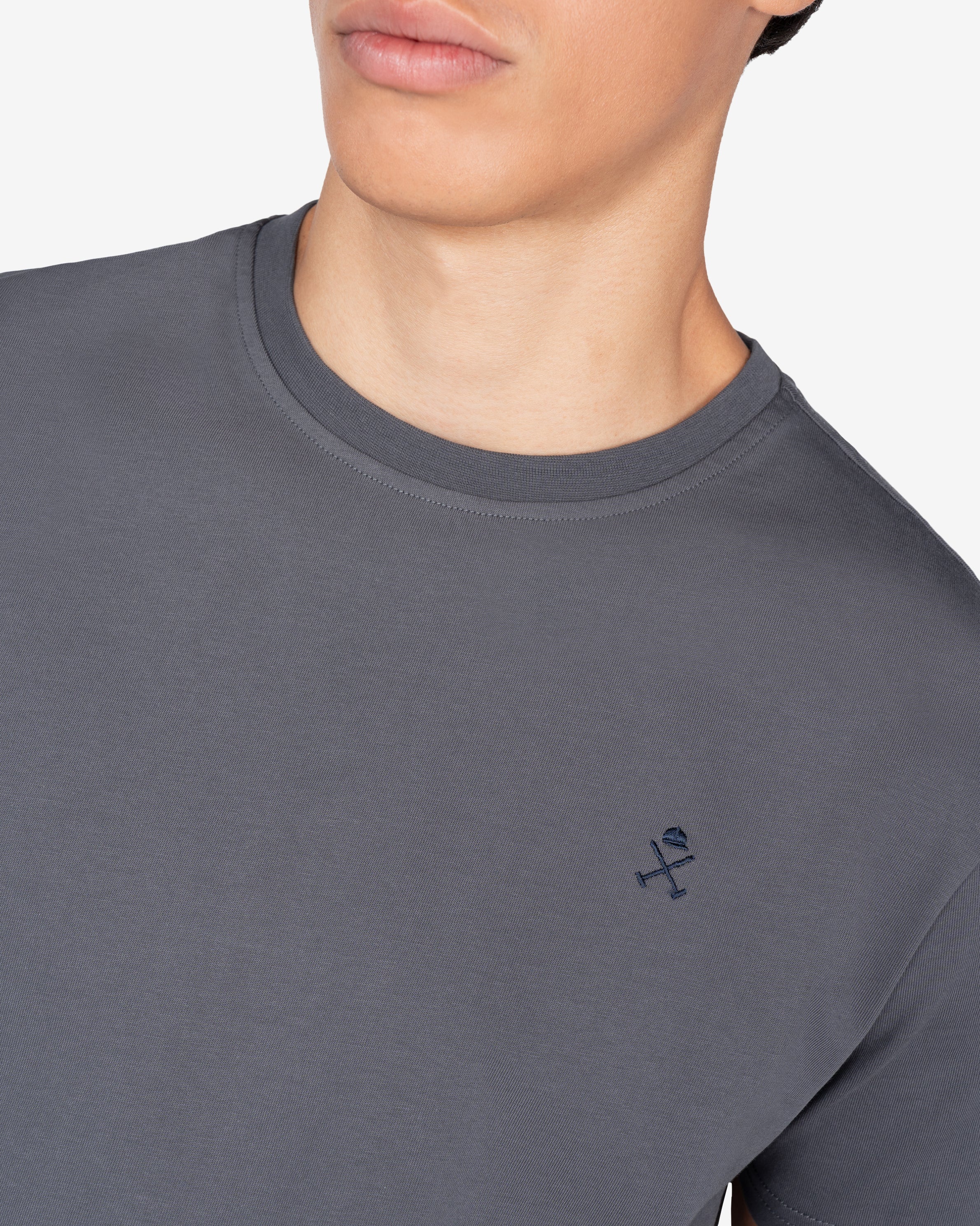 Detalle del logo bordado en azul marino sobre antracita de la camiseta PARADISE de Harper & Neyer