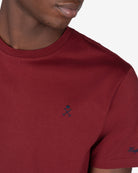 Detalle del logo bordado en azul marino sobre burdeos de la camiseta PARADISE de Harper & Neyer