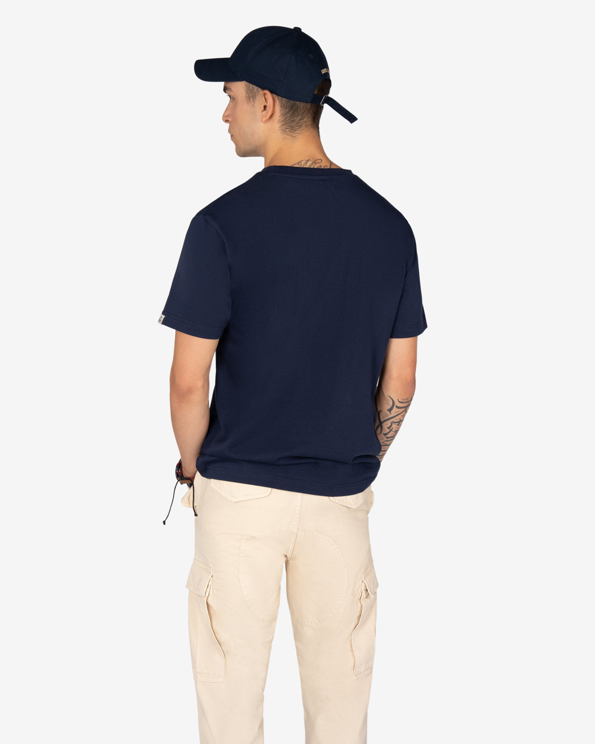 Camiseta ROCKING HORSE azul marino de Harper & Neyer, vista trasera con modelo, gorra y pantalón cargo crudo