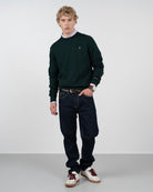 Jersey ICON de Harper & Neyer en verde botella, vista frontal completa con vaquero oscuro y sneakers