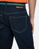 Detalle del bolsillo trasero del Pantalón Denim con logo bordado tonal, parche de cuero Estab. 1985 y cinturón bicolor