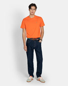 Pantalón Denim de Harper & Neyer en azul oscuro con modelo, combinado con camiseta naranja y sneakers blancas