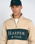 Sudadera Half-Zip Maryland de Harper & Neyer en camel con panel verde bosque, gorra y sneakers verdes