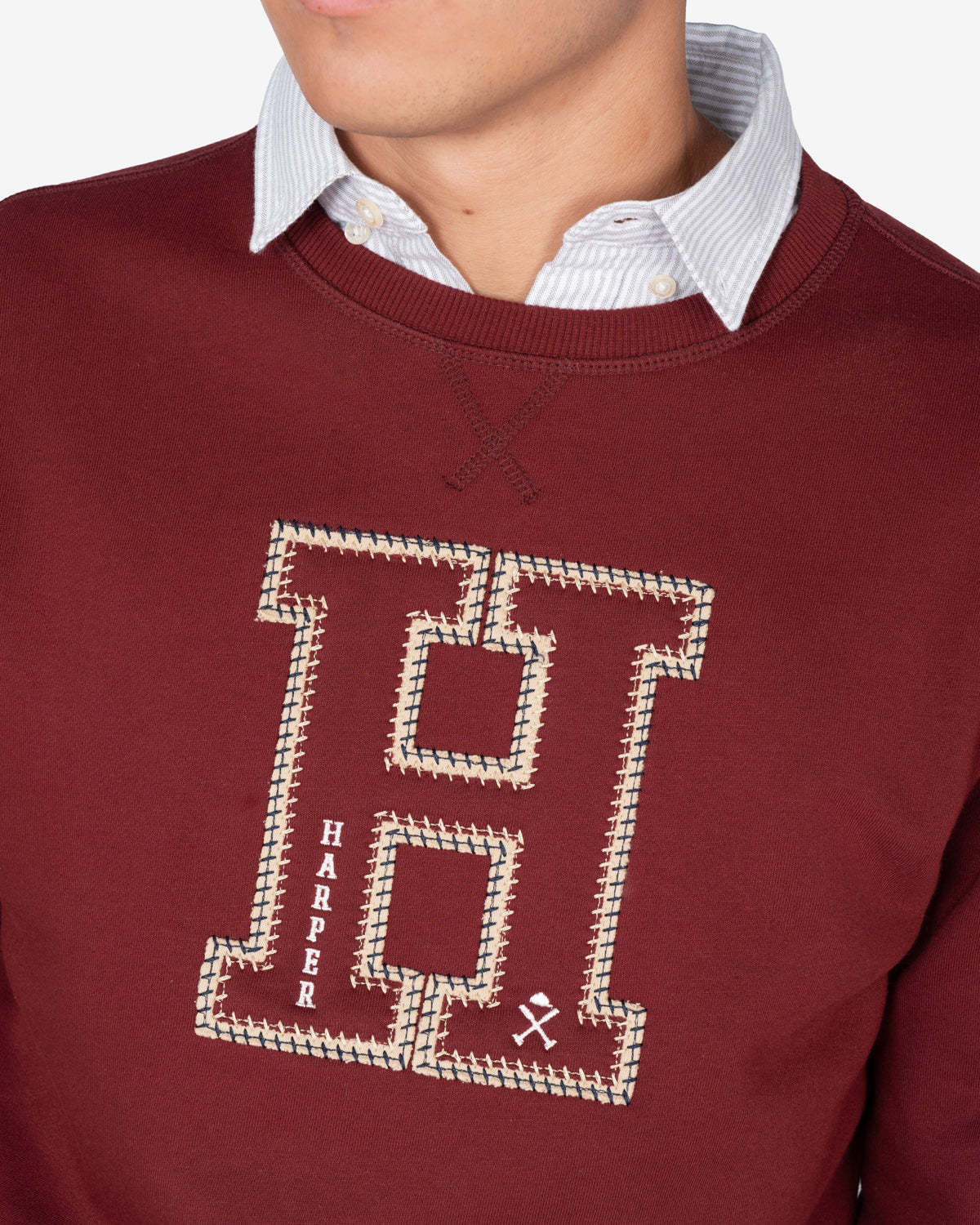Detalle de la H bordada en appliqué crudo con cadeneta dorada y detalles HARPER y casco de la sudadera HARVARD burdeos