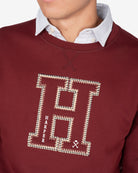 Detalle de la H bordada en appliqué crudo con cadeneta dorada y detalles HARPER y casco de la sudadera HARVARD burdeos