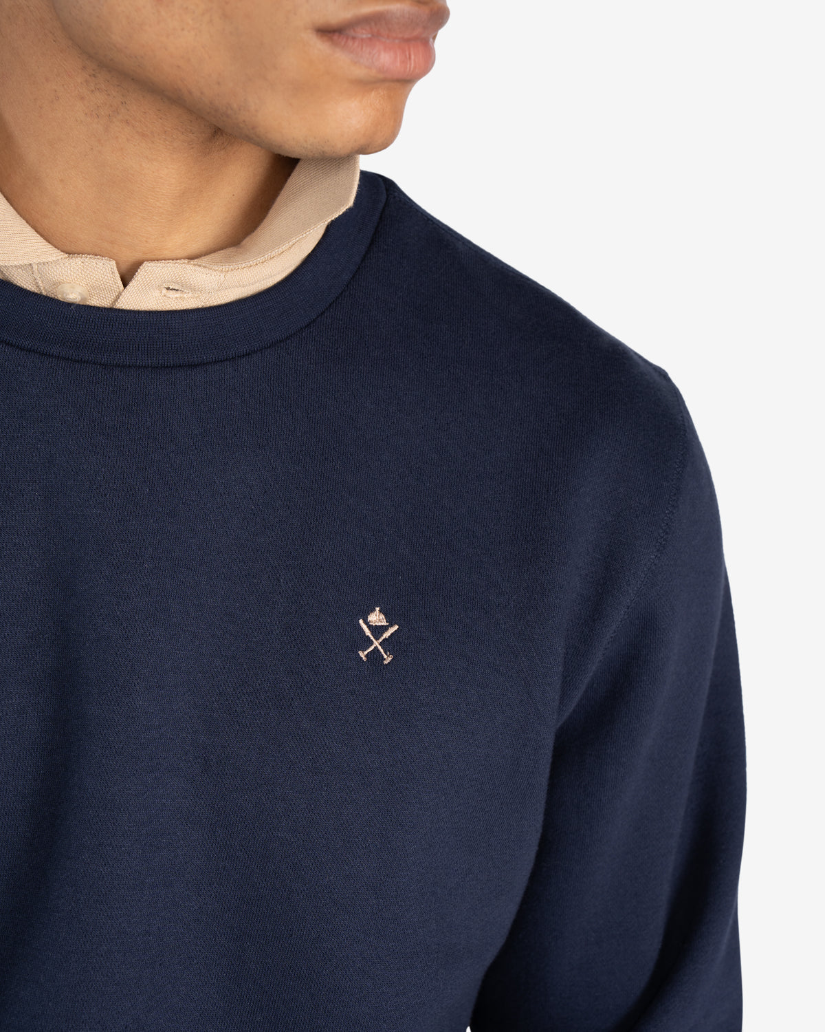 Detalle del logo bordado en crudo sobre azul marino de la sudadera ICON de Harper & Neyer
