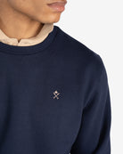 Detalle del logo bordado en crudo sobre azul marino de la sudadera ICON de Harper & Neyer