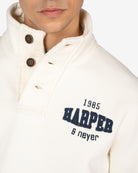 Detalle de la tapeta de tres botones con bordes deshilachados y bordado 1985 Harper Neyer de la sudadera RAVENS crudo