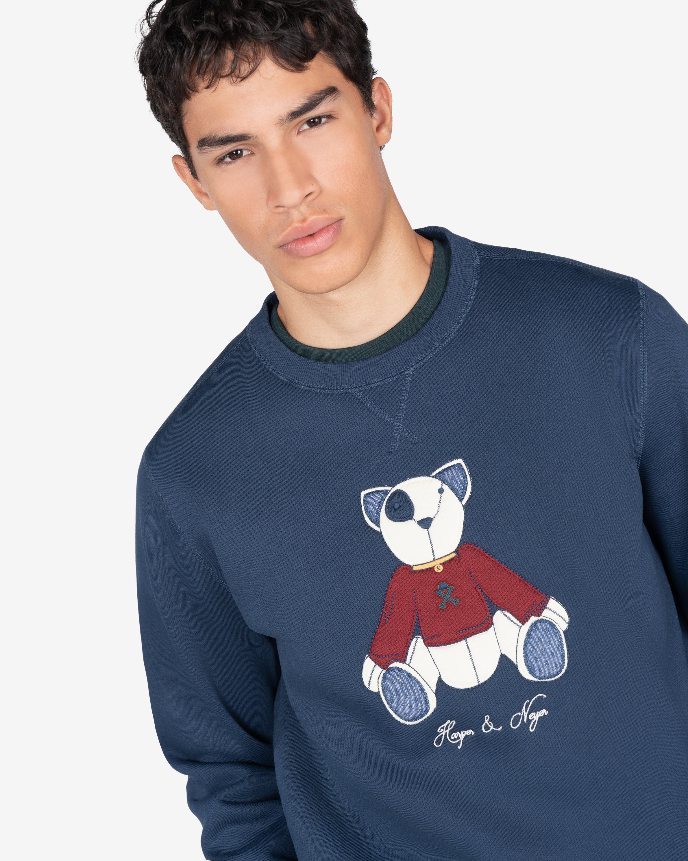 Sudadera TEDDY de Harper & Neyer en azul marino, plano medio con oso appliqué y camiseta verde botella asomando