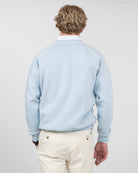 Sudadera VICTORY en algodón azul cielo de Harper & Neyer, vista trasera con manga ranglan sobre camisa de rayas
